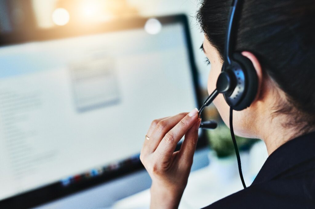 Die Anfragen des Tages verwalten. Rückansicht einer jungen Frau, die in einem Callcenter arbeitet.