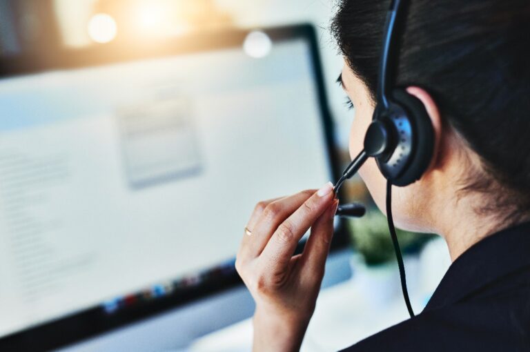 Die Anfragen des Tages verwalten. Rückansicht einer jungen Frau, die in einem Callcenter arbeitet.
