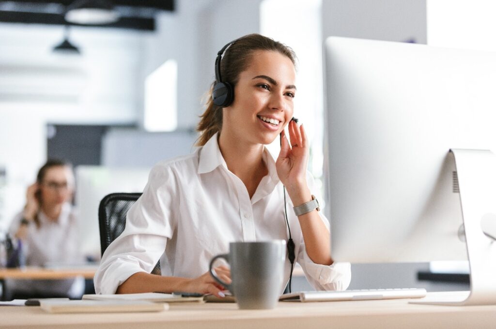 Geschäftsfrau in einem Büro-Callcenter, die mit einem Computer arbeitet und Kopfhörer trägt.