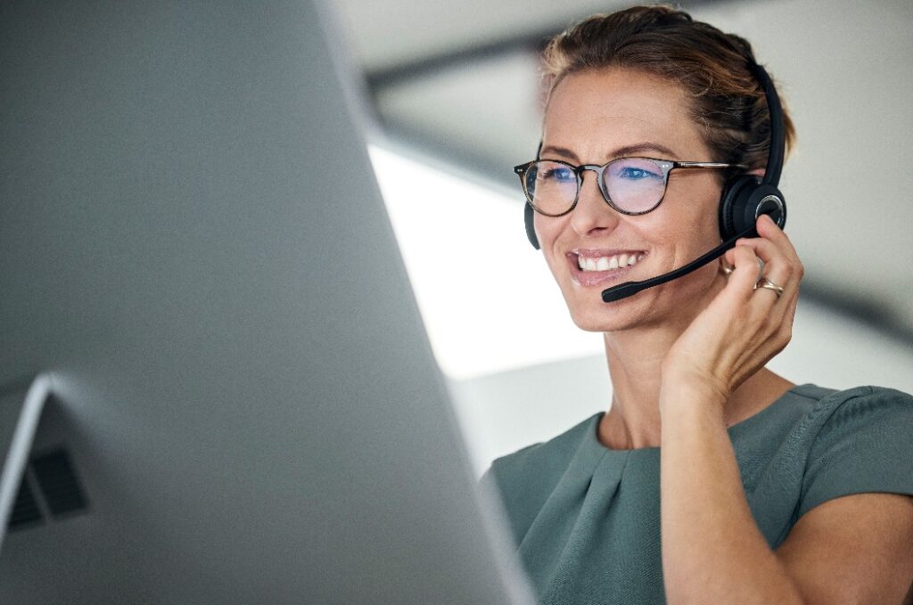 Glücklicher Callcenter-Agent, der online über ein Headset berät.