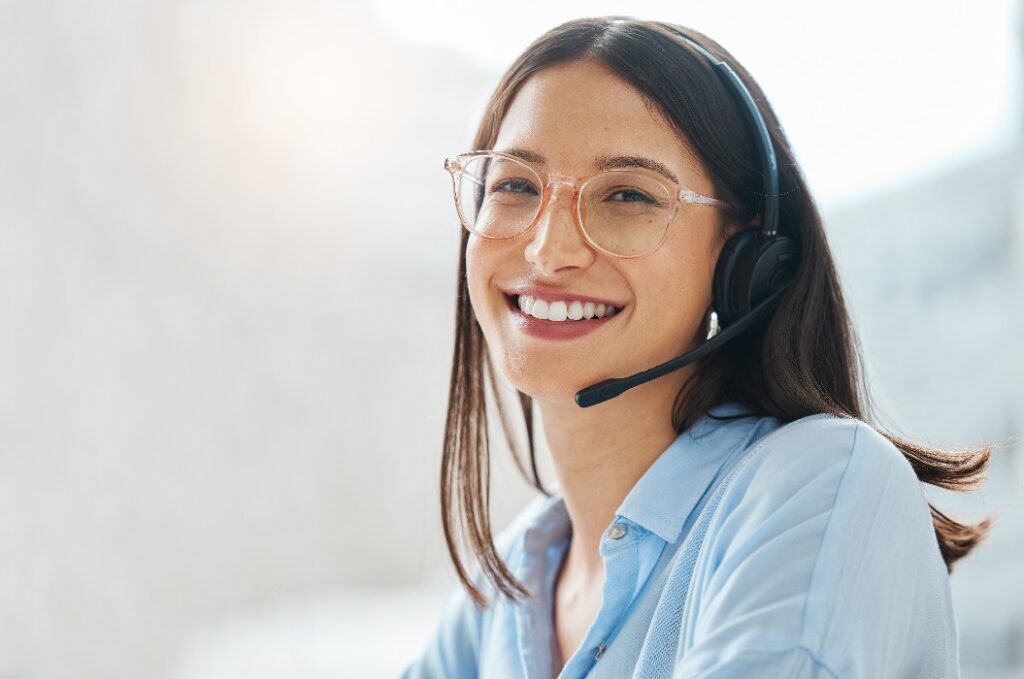 Aufnahme einer attraktiven jungen Verkäuferin, die allein im Büro sitzt und ein Headset trägt.