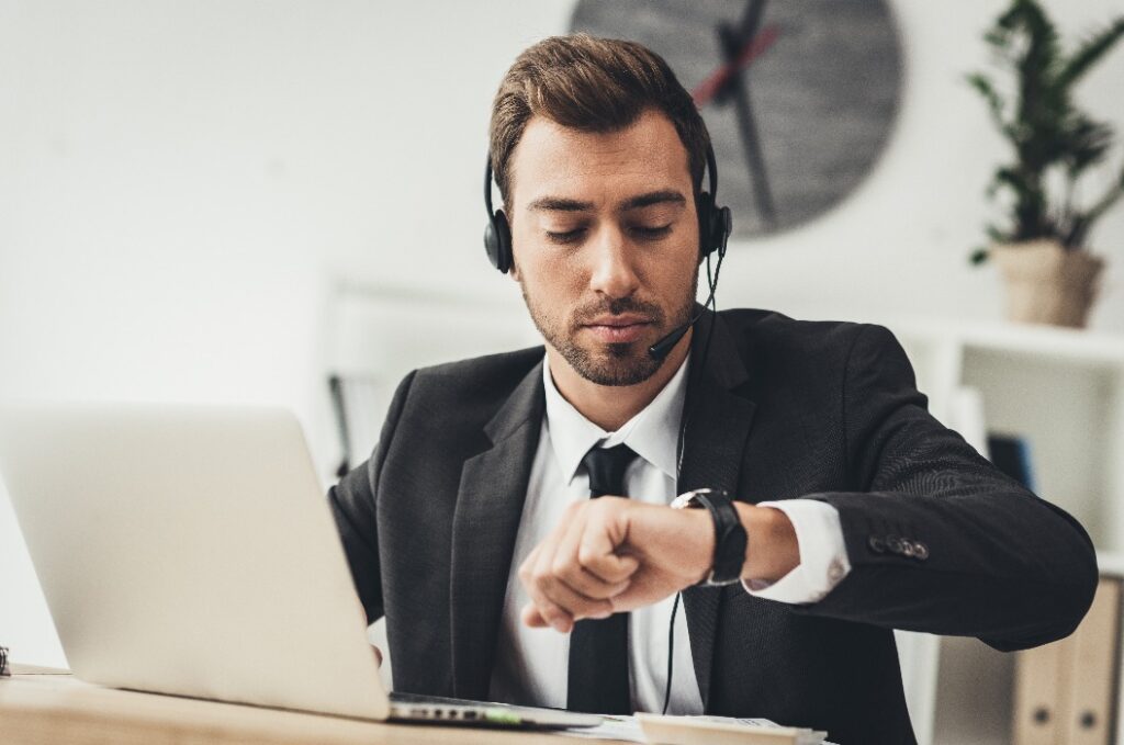 Mitarbeiter im Callcenter blickt auf seine Armbanduhr