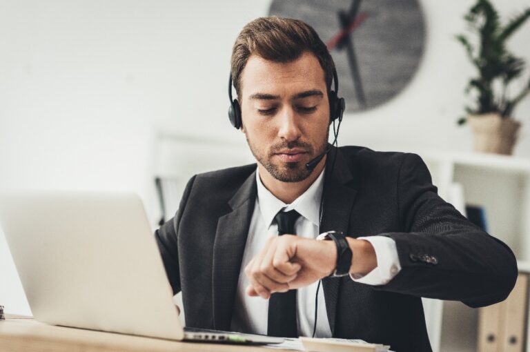 Mitarbeiter im Callcenter blickt auf seine Armbanduhr
